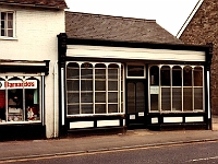 High Street Stanstead Abbotts. Barnardos charity shop. Formerly a hairdressers. The building to the right was the doctors surgery. The opening to the right of the picture is Glenmire Terrace. Rebuilt as "Kateman Court". Photo 1985.